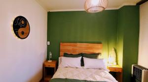 a bedroom with a green wall with a bed and a clock at ORIGEN Centro in El Bolsón +5 photos