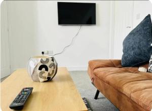 a living room with a couch and remote controls on a coffee table at Maize Walk Retreat - Ashford Beauty in Ashford