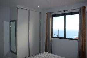 Un dormitorio con ventana y una cama con colcha. en Nature Apartment 1 with Pool, en Arco da Calheta