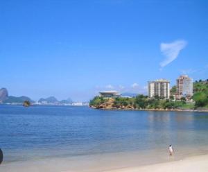 a person standing on a beach near the water at Apto novo perto da UFF e Plaza in Niterói