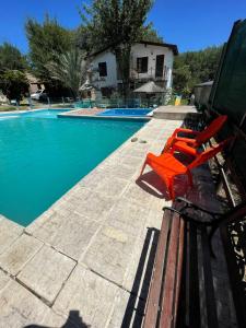 a pair of red chairs sitting next to a swimming pool at Santa Rosa Cabañas in Santa Rosa de Calamuchita +6 photos