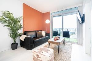 a living room with a black leather couch and a plant at Modern Condo with AC Gym and Parking near Olympic Village for 5 in Vancouver