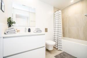 a white bathroom with a toilet and a shower at Modern Condo with AC Gym and Parking near Olympic Village for 5 in Vancouver +24 photos