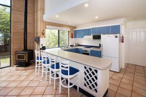 a kitchen with blue cabinets and a counter with bar stools at Tresco, Town central-beach end in Dunsborough