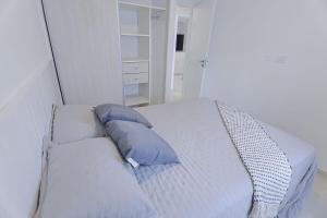 a white bed with blue pillows in a bedroom at Dpto Belgrano II - Santa Fe in Santa Fe
