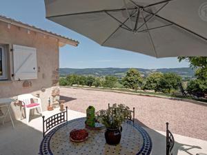 un patio con un tavolo e un ombrellone di Gîte 4 pers, terrasse & jardin, près des Bois Noirs - FR-1-496-348 a Saint-Priest-la-Prugne