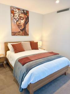a bedroom with a large bed with a painting on the wall at New High Floor Apartment in the heart of Canberra in Canberra