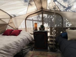 a bedroom with a tent with a bed and a couch at Glamping Puertecillo Surf & Camp in Puertecillo