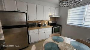 a kitchen with white cabinets and a stainless steel refrigerator at Bienvenue Chez Mymy! in Sept-Îles