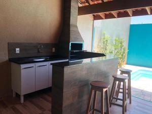 a kitchen with a bar with stools and a pool at Recanto Julia in Olímpia