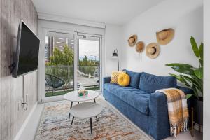 a living room with a blue couch and a large window at Eco-Friendly Condo with AC Gym and Parking near SkyTrain for 5 in Vancouver