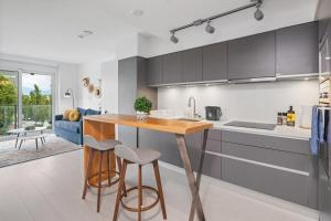 a kitchen with a wooden table and two stools at Eco-Friendly Condo with AC Gym and Parking near SkyTrain for 5 in Vancouver +14 photos