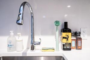 a kitchen sink with a faucet and a bottle of alcohol at Eco-Friendly Condo with AC Gym and Parking near SkyTrain for 5 in Vancouver