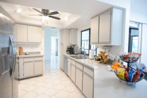Una cocina con gabinetes blancos y un refrigerador. en House With A Boat - Boat, Heated Pool, Fishing, en Cabo Coral