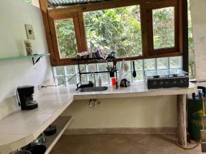 a kitchen with a counter with a sink and a window at cabaña tibiki, minca in Minca