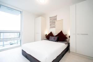 バンクーバーにあるBright Condo with AC and Parking near Science World for 4 Guestsの白いベッドと大きな窓のある寝室