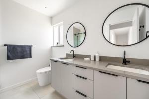 a white bathroom with a sink and a mirror at Luxury&Brand-new 3BD 2BTH House in Burnaby