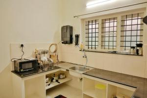 una cucina con un lavandino e un microonde su un bancone di Nila Heavens - Spacious 5 BHK Homestay , ideal for families a Guruvayoor Altre 49 foto