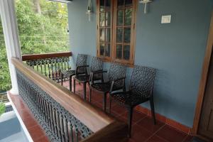 un gruppo di sedie seduto sopra un balcone di Nila Heavens - Spacious 5 BHK Homestay , ideal for families a Guruvayoor