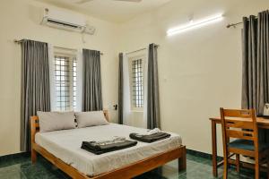 una camera da letto con un letto con una scrivania e una sedia di Nila Heavens - Spacious 5 BHK Homestay , ideal for families a Guruvayoor