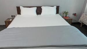 a large white bed with two pillows on it at Udayachal House in Bindukuri
