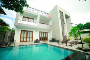 a villa with a swimming pool in front of a house at Stadler Resort in Wadduwa