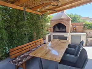 苏佩塔尔Calypso - newly equiped, with separate entrance and parking的一个带木桌和比萨饼烤箱的庭院