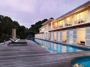 
a beach with a pool, chairs, and a bench at Amara Sanctuary Resort Sentosa (SG Clean, Staycation Approved) in Singapore
