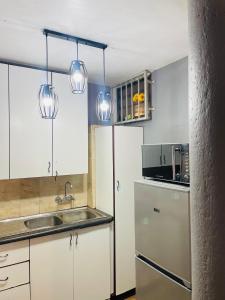 a kitchen with a sink and a refrigerator and lights at Cloud 10 Hideaway in Pretoria