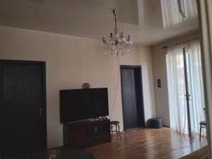 a living room with a flat screen television and a chandelier at Семейныи номер двумя спальнями in K'obulet'i