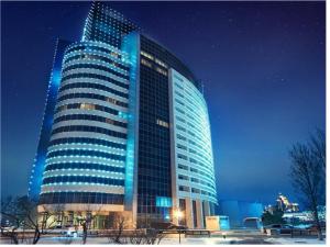 un grand bâtiment avec des lumières bleues allumées la nuit dans l'établissement Hotel Duman, à Astana