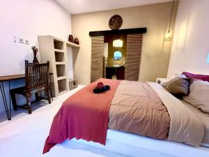 Un dormitorio con una cama grande con una manta roja. en Pondok Dembe, en Uluwatu