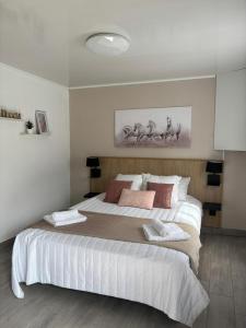 - une chambre dotée d'un grand lit avec des draps blancs et des oreillers roses dans l'établissement Lamézon Entre-deux Location Saisonnière, à Entre-Deux