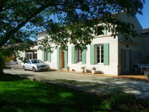 a car parked in front of a white house at Gîte cosy, sur jardin, terrasse privée, parking au calme en rdc in Gémozac