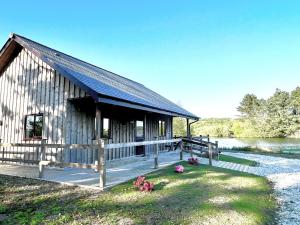 a small wooden building with a deck next to a lake at Kingfisher Lodge in St Austell