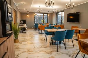 a dining room with tables and blue chairs at Volotel SkyWay in Cluj-Napoca