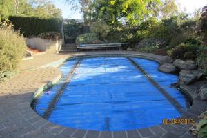 une grande piscine bleue avec un banc dans un jardin dans l'établissement The cashmere bothy, à Christchurch