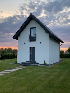 a white house with a black roof on a green field at Domek pod Sosnową Górą in Żelazno +50 photos