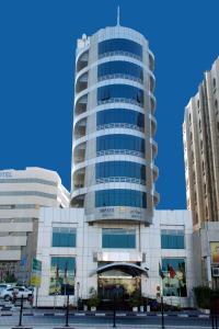 a tall glass building with a blue sky in the background at Monaco Hotel in Dubai