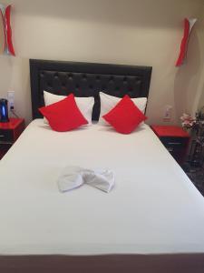 a white bed with red pillows and a bow tie on it at Apartmani Vesna Luxury & Michel ap 9 in Paralia Katerinis