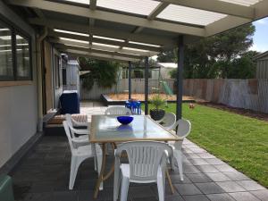 a patio with a table and chairs under a pergola at The Dunes Beach House in Goolwa