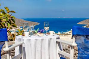 a table with wine glasses and food on top of the ocean at Skopelitis Village in Katapola