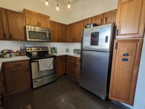 Una cocina con gabinetes de madera y un refrigerador de acero inoxidable. en Urbenity, en Irving