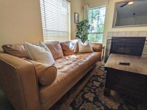 un sofá de cuero marrón en una sala de estar con chimenea en Urbenity, en Irving