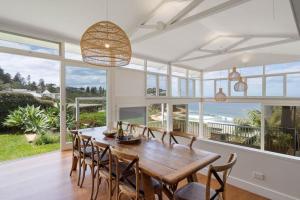 纽波特The Bungan - Beachfront W Access To Bungan Beach的一间有桌子、椅子和大海的餐厅