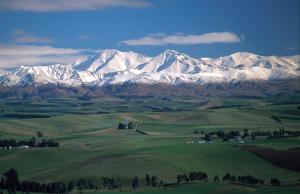 a mountain range with snow covered mountains in a green field at Alpine Motel in Oamaru +43 photos