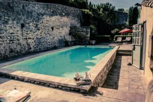 une grande piscine avec un mur en pierre dans l'établissement Hotel de L Orange, à Sommières