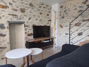 un soggiorno con una TV, un divano e un tavolo di Maison de ville cosy avec jardin, à 300 m de la plage & restaurants a Binic