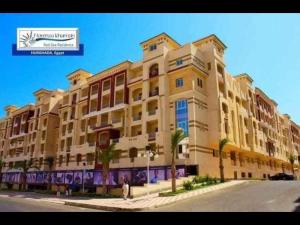 a large yellow building with palm trees in front of it at كمباوند فلورينزا 50 in Hurghada +3 photos