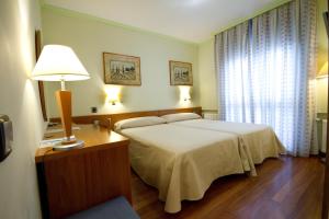a bedroom with a bed and a table with a lamp at Hotel Los 5 Pinos in Madrid